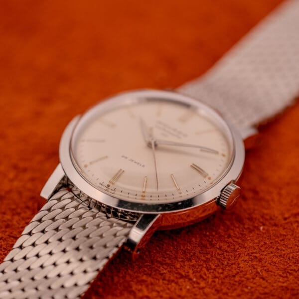 The Movado Automatic 431 Ref. 11201 features a stainless steel case and bracelet, elegantly displayed on an orange textured surface.