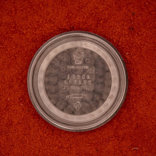 A Movado Automatic 431 Ref. 11201 with a stainless steel case and bracelet, displayed on a red textured surface.