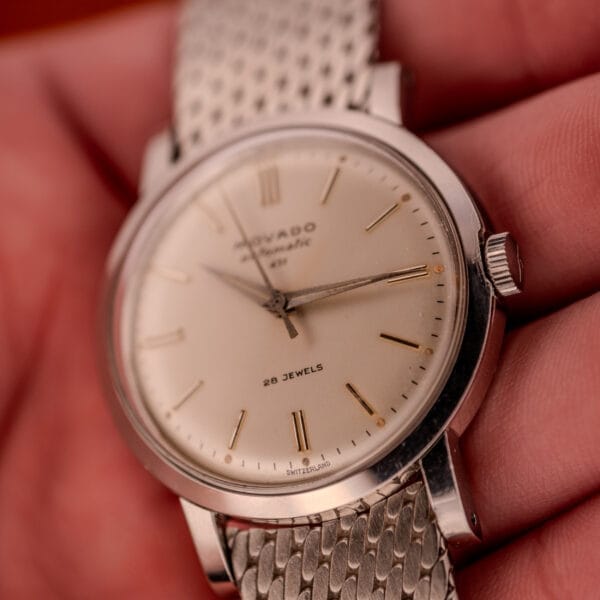 Close-up of a vintage Movado Automatic 431 Ref. 11201, showcasing its stainless steel case and bracelet with a cream dial and gold hour markers.