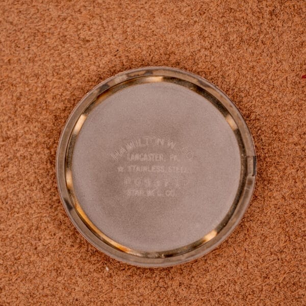 A round metal watch case back engraved with HAMILTON W. CO, LANCASTER, PA, and Stainless Steel Case rests on cork—an authentic detail from the Hamilton Sea-Crest Stainless Steel Case & White Dial Cal. 673.