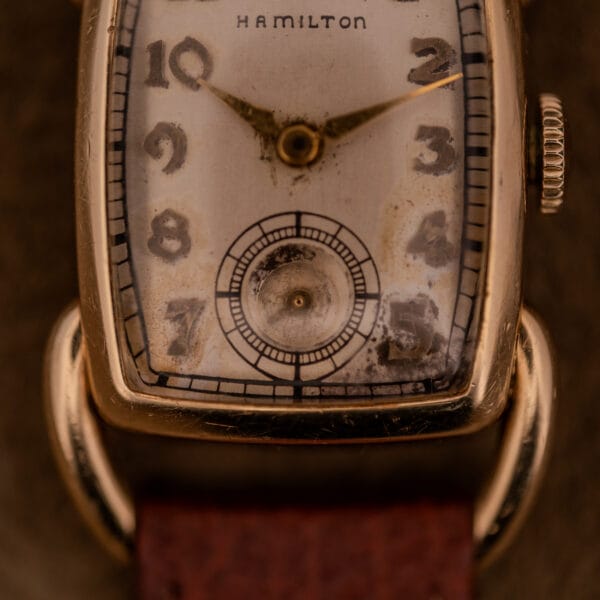 Close-up of the Hamilton Bowman Art Deco 10k Gold Filled Case Manual Wind Cal. 980 wristwatch, showcasing its tarnished dial, worn leather strap, and refined Art Deco details.