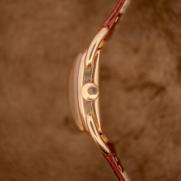 Side view of a Hamilton Bowman Art Deco 10k Gold Filled Case Manual Wind Cal. 980 wristwatch with a brown leather strap against a blurred brown background.