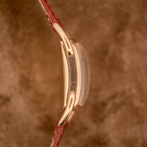 Side view of a Hamilton Bowman Art Deco 10k Gold Filled Case Manual Wind Cal. 980 with brown leather strap, displayed against a brown textured background.