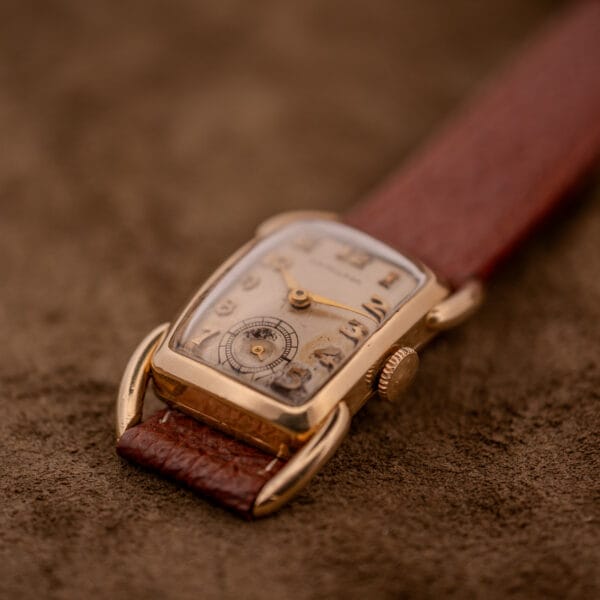 Hamilton Bowman Art Deco 10k Gold Filled Case Manual Wind Cal. 980 wristwatch with a brown leather strap, displayed on a brown textured surface.