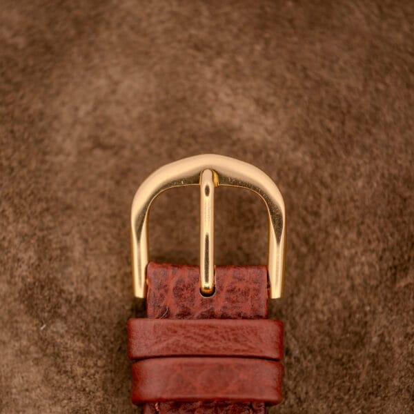 Close-up of the Hamilton Bowman Art Deco 10k Gold Filled Case Manual Wind Cal. 980 featured on a brown leather strap, set against a soft brown textured background.