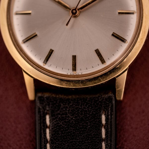 Close-up of a Zodiac Hermetic Ref. 673 853 with a gold case, black leather strap, and sunburst dial, shown with original box and papers.