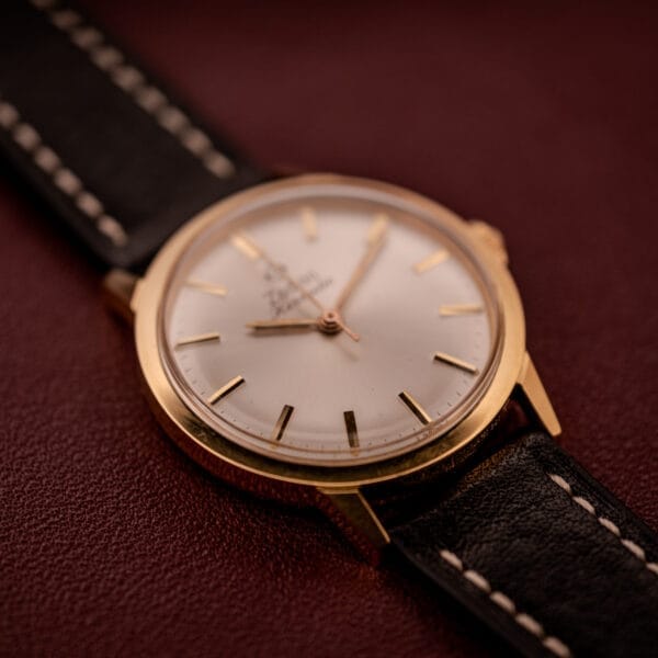 Zodiac Hermetic Ref. 673 853 with a gold case, black leather strap, and sunburst white dial with gold markers—classic style, shown on brown surface. Includes original box & papers.