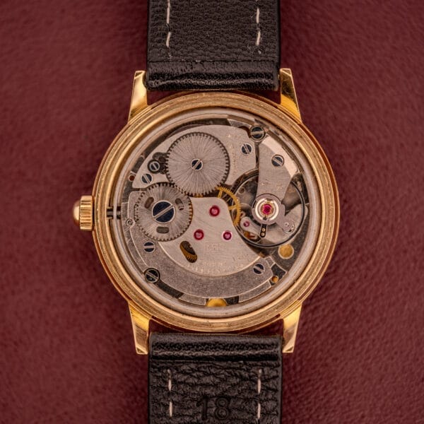 The Zodiac Hermetic Ref. 673 853 features a sunburst dial, visible mechanical gears, and a black leather strap, shown on a brown background. Includes original box and papers.