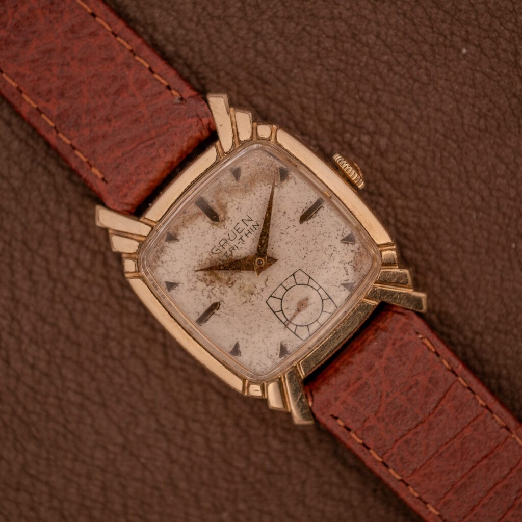 Gruen Veri-Thin Ref. 415-810 Art Deco Lugs Manual Wind Cal. 415 wristwatch with brown leather strap on a textured brown surface, displaying timeless Art Deco style and vintage charm.