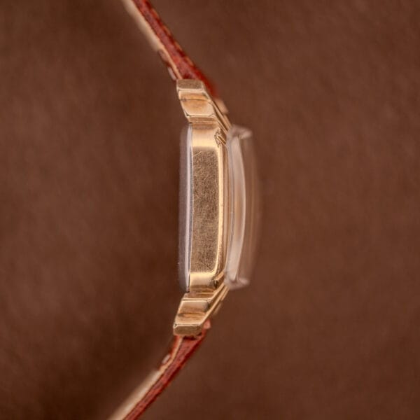 Side view of a Gruen Veri-Thin Ref. 415-810 with Art Deco lugs and brown leather strap, manual wind Cal. 415, set against a brown background.