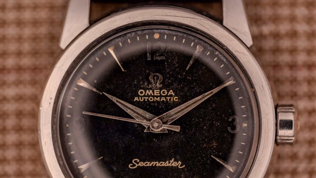 Close-up of a vintage Omega Seamaster Automatic wristwatch featuring one of the classic black dials and a sleek silver case.