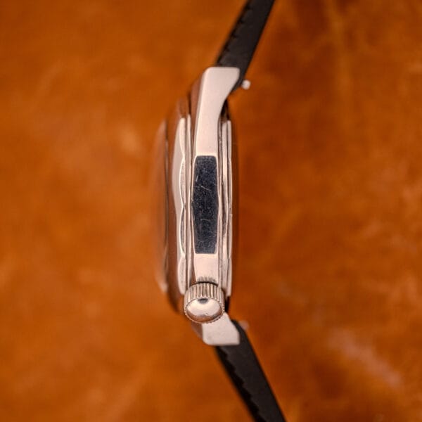 Side view of a Zenith Automatic Defy NA.50.012.2 in stainless steel Cal. 2562 PC, featuring a black strap, set against a brown background.