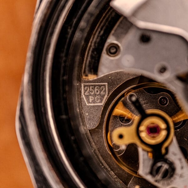 Close-up of the Zenith Automatic Defy NA.50.012.2 in stainless steel, showcasing its Cal. 2562 PC movement with visible gears and an engraved 2562 PC marking on the component.