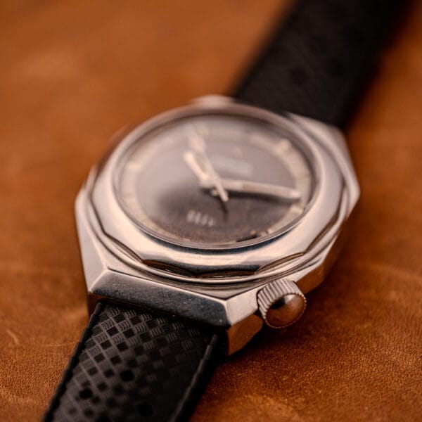 Close-up of a Zenith Automatic Defy NA.50.012.2 in stainless steel, Cal. 2562 PC, featuring a black strap, displayed on a brown surface.