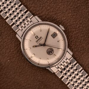An Omega Automatic Ref. 166.020 for U.S. Steel Presentation Watch, featuring a silver metal band, date display, and USS dial detail, is showcased on brown leather.