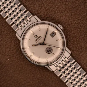 An Omega Automatic Ref. 166.020 for U.S. Steel Presentation Watch, featuring a silver metal band, date display, and USS dial detail, is showcased on brown leather.