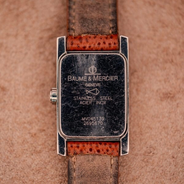 Close-up of a worn Baume Mercier Hampton MV045139 Copper Dial Stainless Steel watch back with leather strap, showing engraved stainless steel details.