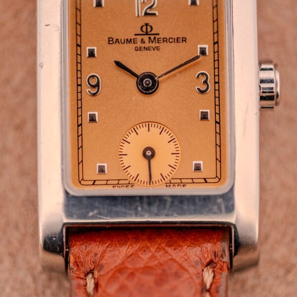 Close-up of the Baume Mercier Hampton MV045139 watch with a copper dial, stainless steel case, and brown leather strap.
