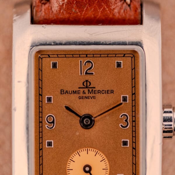 Close-up of a Baume Mercier Hampton MV045139 with a copper dial, stainless steel case, black hands, and brown leather strap.