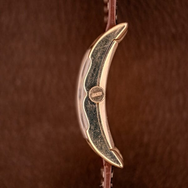 Side view close-up of a Gruen Curvex Precision Ref. 370-600 with a 10k Gold Filled Case, displayed on a brown textured leather surface.