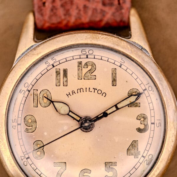 Close-up of a vintage Hamilton WWII Era U.S. Military Cal. 987S Hacking Seconds watch, showing its worn face and brown leather strap.