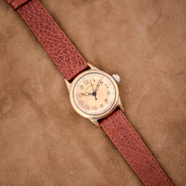 Hamilton WWII Era U.S. Military Cal. 987S Hacking Seconds wristwatch with brown leather strap, shown on tan suede. Features hacking seconds for precise time setting.