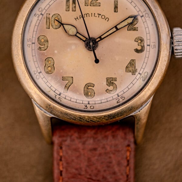 Close-up of a Hamilton WWII Era U.S. Military watch featuring the Cal. 987S Hacking Seconds movement, worn dial, and brown leather strap.