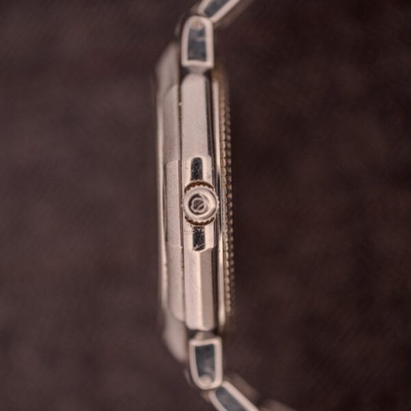 Close-up side view of the Baume Mercier Riviera Automatic MV045165 Guilloché Dial crown set against a blurred dark background.