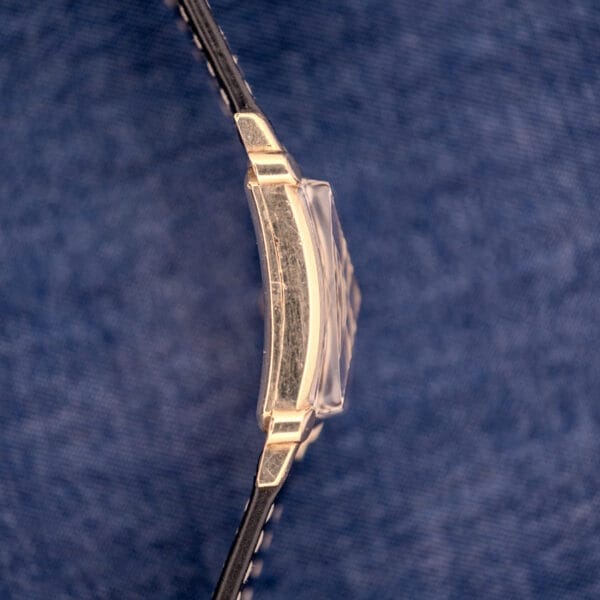 Side view of the Gruen Curvex Ref. 370-642 Art Deco “Pyramid” Crystal wristwatch with a black strap, displayed on blue denim fabric.