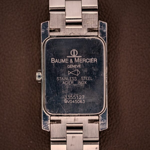 Back of a scratched Baume Mercier Hampton XL MV045063 White Dial Stainless Steel watch with engraved details.