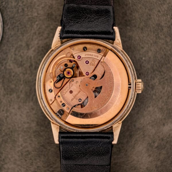 Close-up of the Omega Automatic Ref. LU 6304 "HF" Logo Dial with exposed mechanical movement, black leather strap, and an elegant 10k GF bezel.