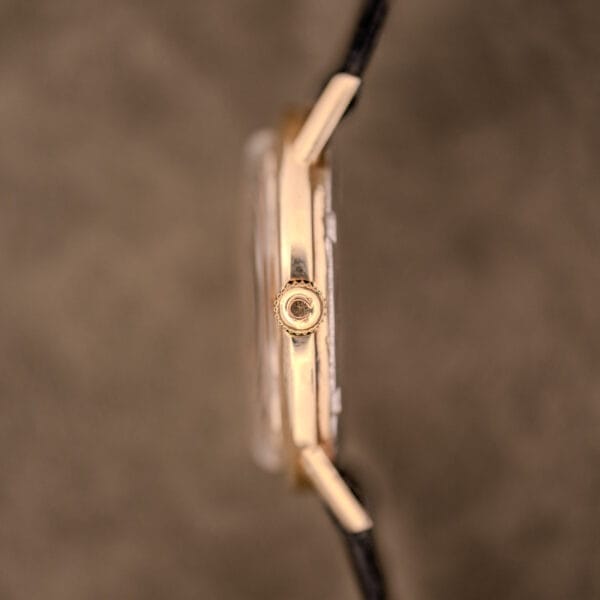 Side view of an Omega Automatic Ref. LU 6304 "HF" Logo Dial wristwatch with a 10k GF bezel and black leather strap, showing the crown and lugs.