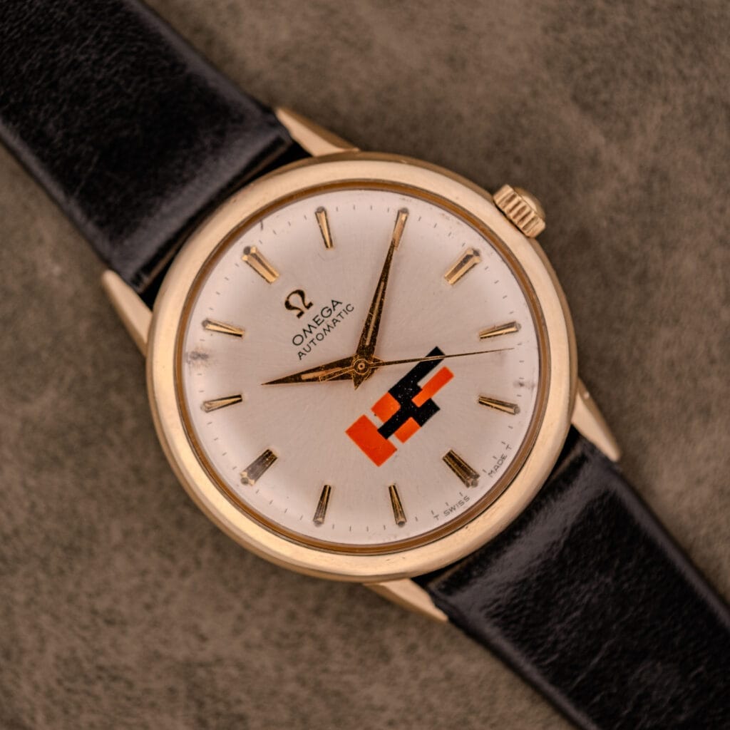 Omega Automatic Ref. LU 6304 with "HF" Logo Dial, 10k GF bezel, and black leather strap. Features a distinctive red-black geometric dial design.