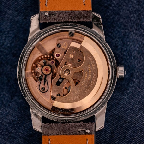 Close-up of an Omega Automatic Seamaster 2846-2848 with a stainless steel case and sunburst dial, showcasing its intricate automatic movement through the transparent back.