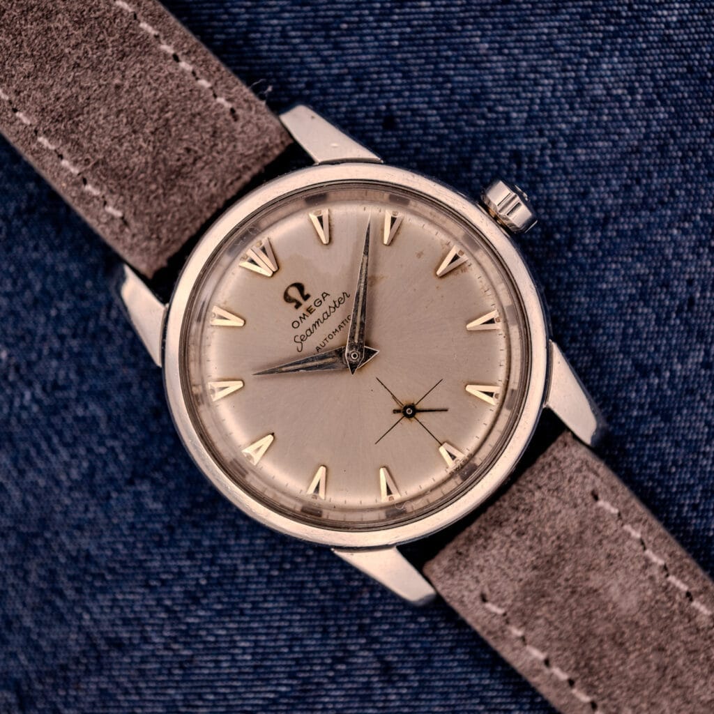 An Omega Automatic Seamaster 2846-2848 Stainless Steel watch with a sunburst dial, stylishly presented on blue denim fabric.