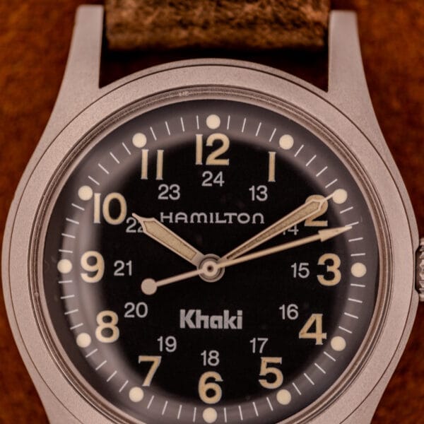 Close-up of the Hamilton Khaki Ref. 9415A with a black dial, beige numerals and hands, brown leather strap, and manual wind stainless steel case.