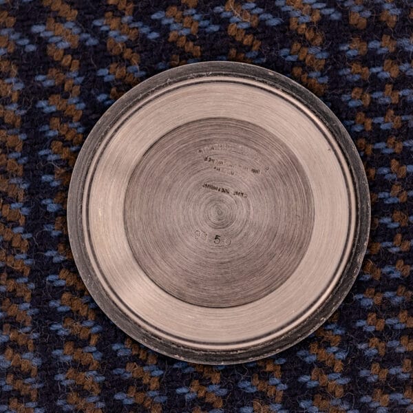 The Tudor Prince-Quartz Oysterdate Ref. 9150 Two-Tone Blue Dial, a round engraved metal watch, is displayed on a blue and brown checkered fabric background.