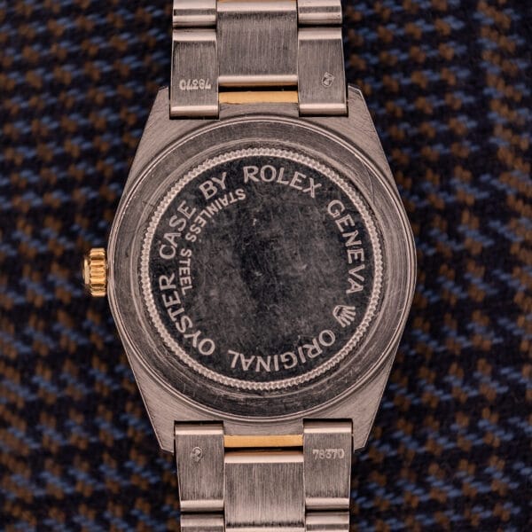 The case back of a Tudor Prince-Quartz Oysterdate Ref. 9150 rests on brown and blue patterned fabric, echoing the style of its Two-Tone Blue Dial.