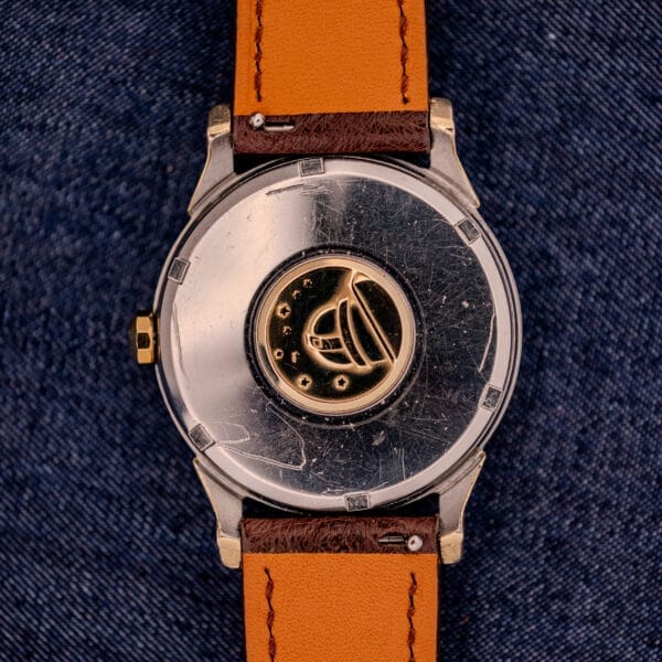 Close-up of the Omega Constellation Pie-Pan Dial Ref. 167.005 14k Gold Capped on brown leather, displayed on denim, showcasing its classic gold detailing.