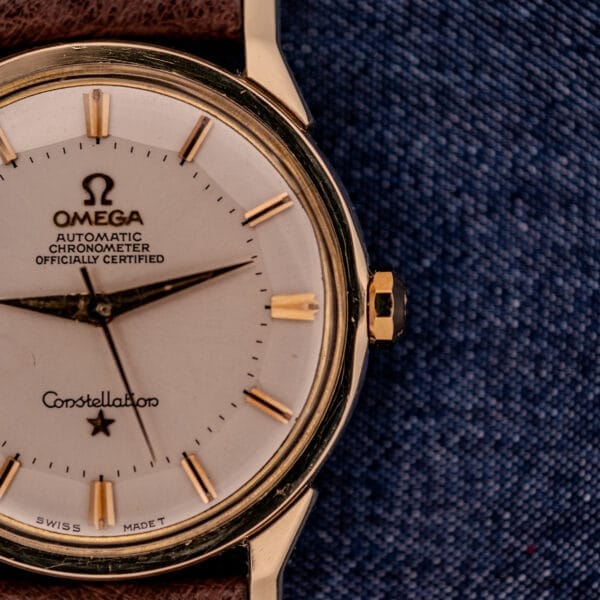 Close-up of the Omega Constellation Pie-Pan Dial Ref. 167.005 with a 14k gold capped case and brown leather strap, showcased on blue denim fabric.