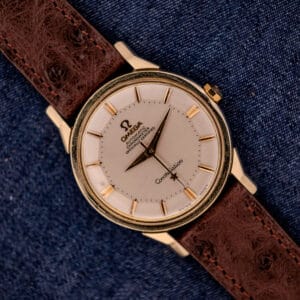 Omega Constellation Pie-Pan Dial Ref. 167.005 with 14k gold capped case, distinctive pie-pan dial, and brown leather strap, elegantly displayed on blue denim fabric.