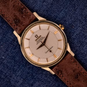 Omega Constellation Pie-Pan Dial Ref. 167.005 with 14k gold capped case, distinctive pie-pan dial, and brown leather strap, elegantly displayed on blue denim fabric.
