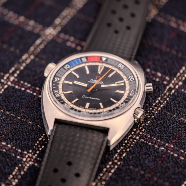 An Omega Seamaster Ref. 145.008 Chronostop Regatta Cal. 865 watch with a black strap rests on a plaid fabric background.