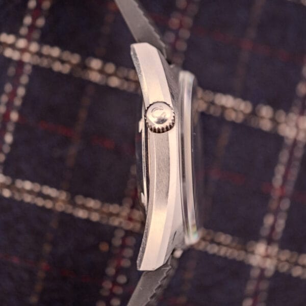 Side view of an Omega Seamaster Ref. 145.008 Chronostop Regatta with Cal. 865 movement and a textured crown, resting on plaid fabric.