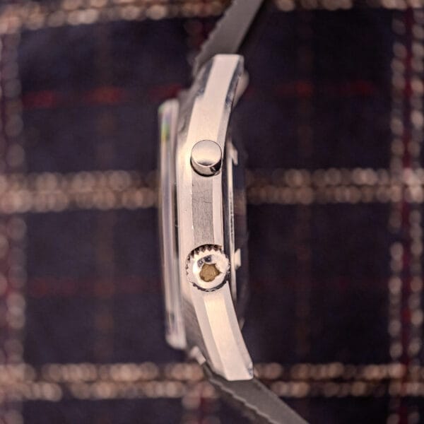 Side view of an Omega Seamaster Ref. 145.008 Chronostop Regatta Cal. 865 wristwatch with a textured crown, held against a plaid fabric background.