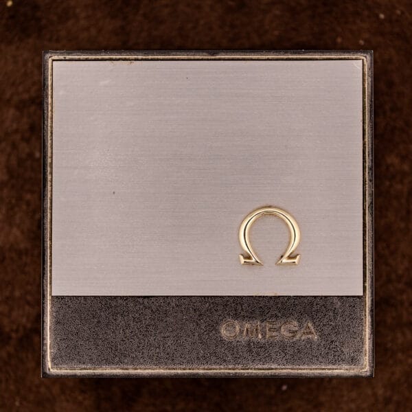 A metallic Omega Constellation Chronometer Ref. 168.045 Day/Date Full Set watch box featuring a gold Omega symbol and OMEGA engraved on a brown background—ideal for storing your timepiece securely and in style.