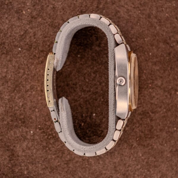 Omega Constellation Chronometer Ref. 168.045 Day/Date Full Set with metal band, side view on a brown textured surface—a classic timepiece for collectors.