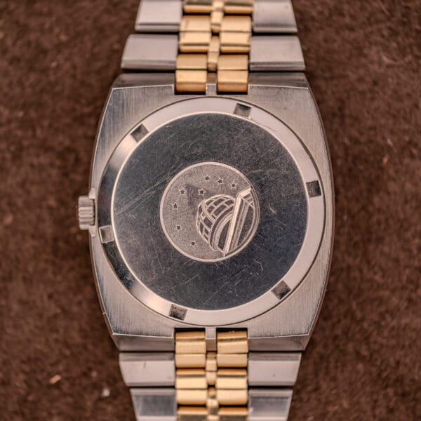 Close-up of the Omega Constellation Chronometer Ref. 168.045 Day/Date Full Set caseback engraved with an observatory and stars motif, shown on a brown surface.