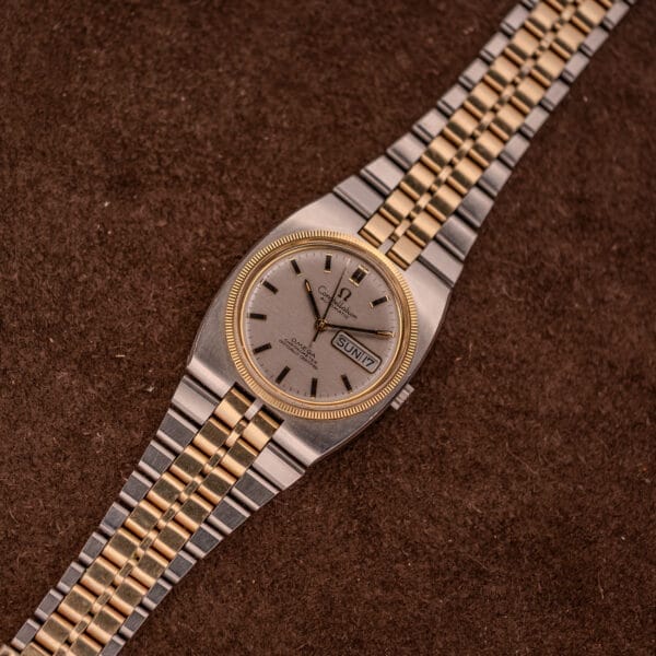 The Omega Constellation Chronometer Ref. 168.045 Day/Date Full Set features a two-tone design with a metal bracelet, gold bezel, and brown day-date dial.