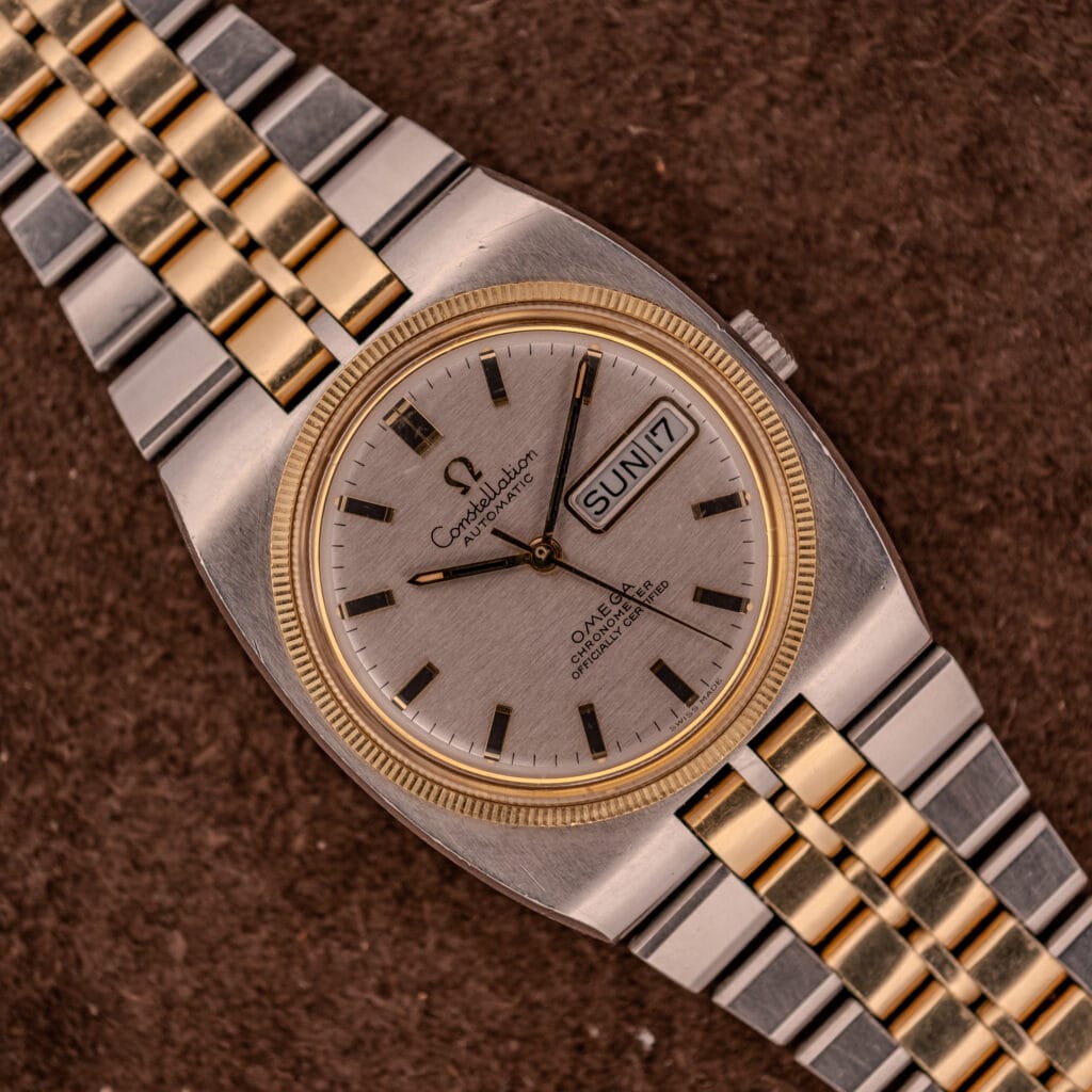 Omega Constellation Chronometer Ref. 168.045 Day/Date Full Set with gold and silver bracelet, featured on a brown background.
